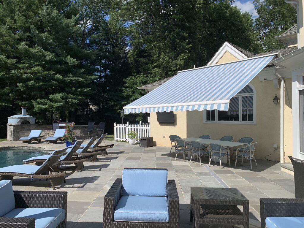 blue and white retractable awning by a pool