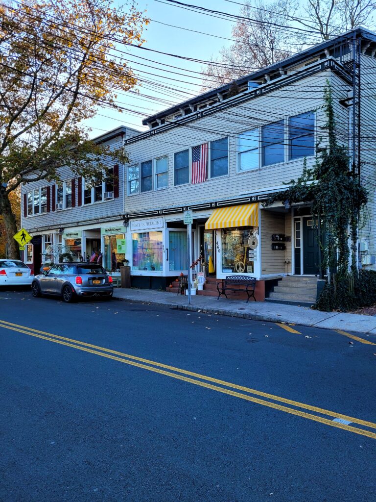 Bright yellow fabric awning with bold stripes over café display window and entryway of Bunbury’s Coffee Shop on Main Street in Piermont.